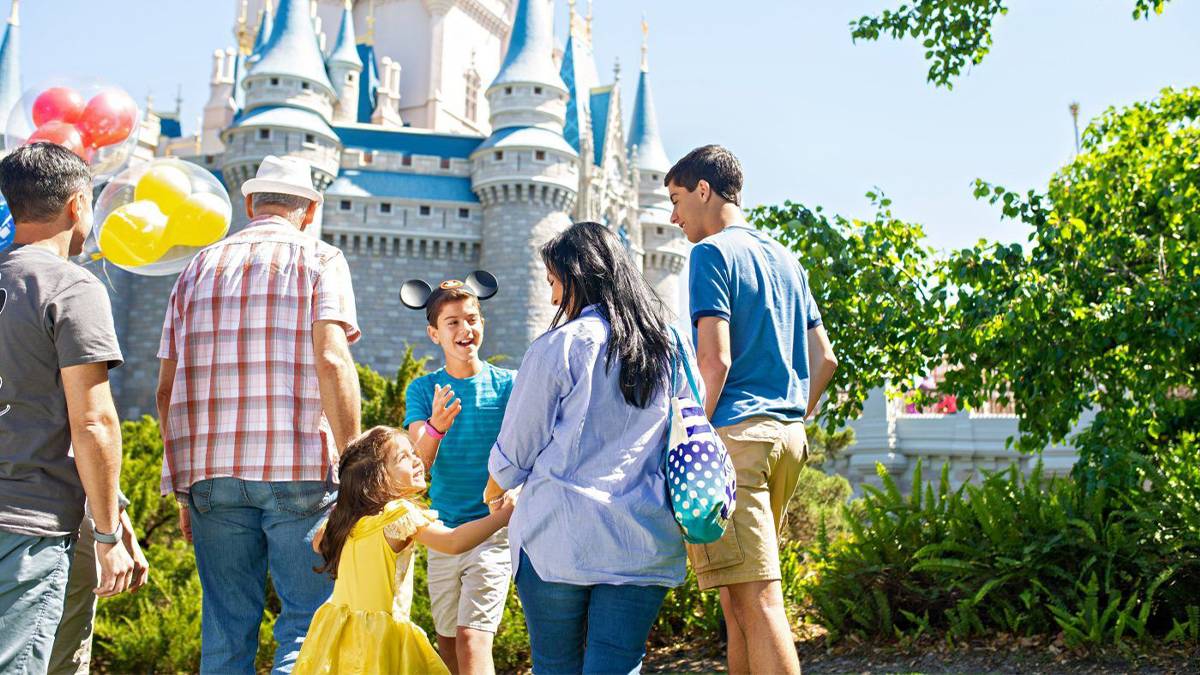 excited family standing in front of disney castle